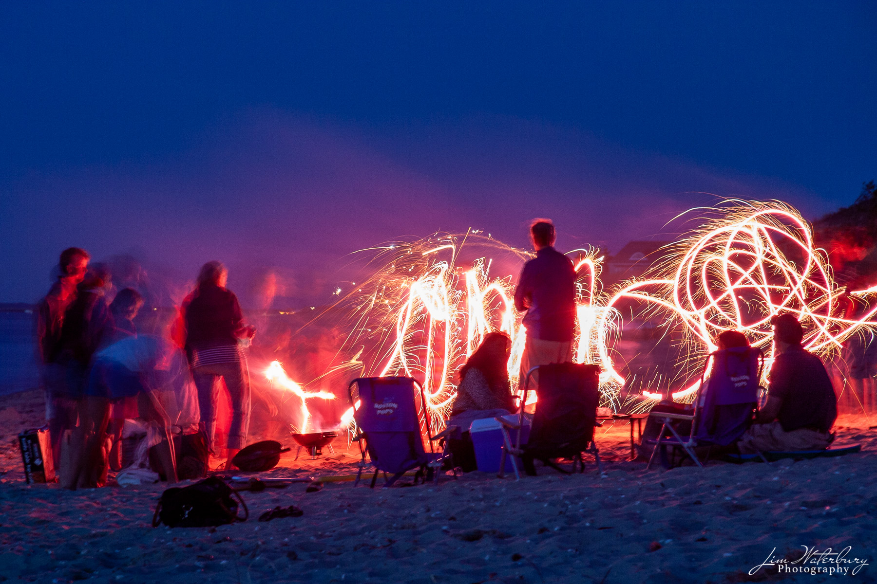 At a family picnic on a beach on the north shore of Nantucket , children draw circles of light in the night with sparklers.