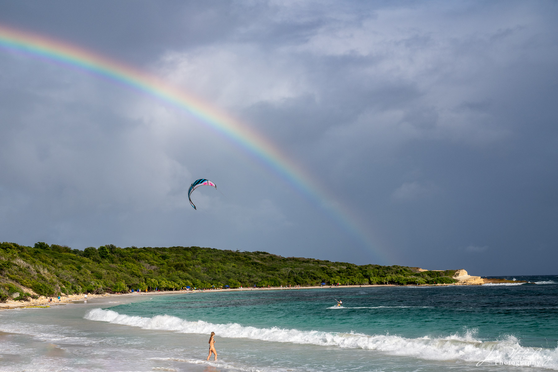 Under the Rainbow A late afternoon scene at Half Moon Bay in Antigua shows a rainbow against dark rain clouds, a woman about to enter the ocean...