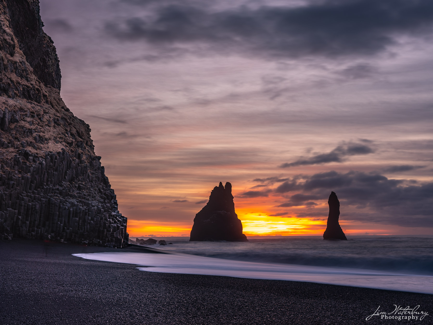 Sea Stacks Reynisdrangar sea stacks are silhouetted by a winter sunrise on the black sand beach at Reynisjara, Iceland.
