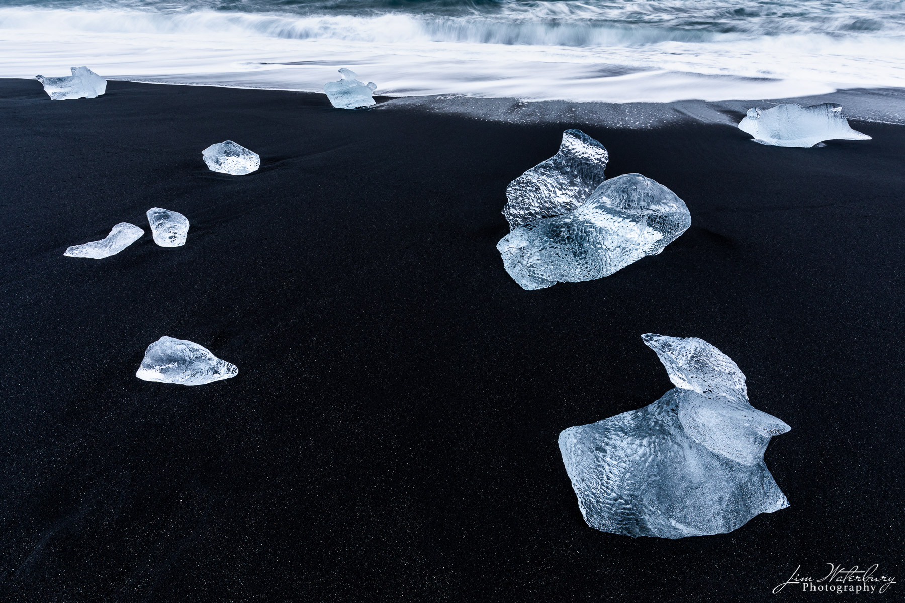 Chunks of ice, resembling large diamonds, dot the black sand at Fellsfjara Beach (or Breidamerkursandur -- Diamond Beach), near...