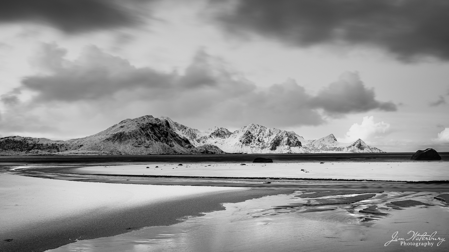 New snow coats the black sands of Haukland Beach, in the Lofoten Islands in Norway.