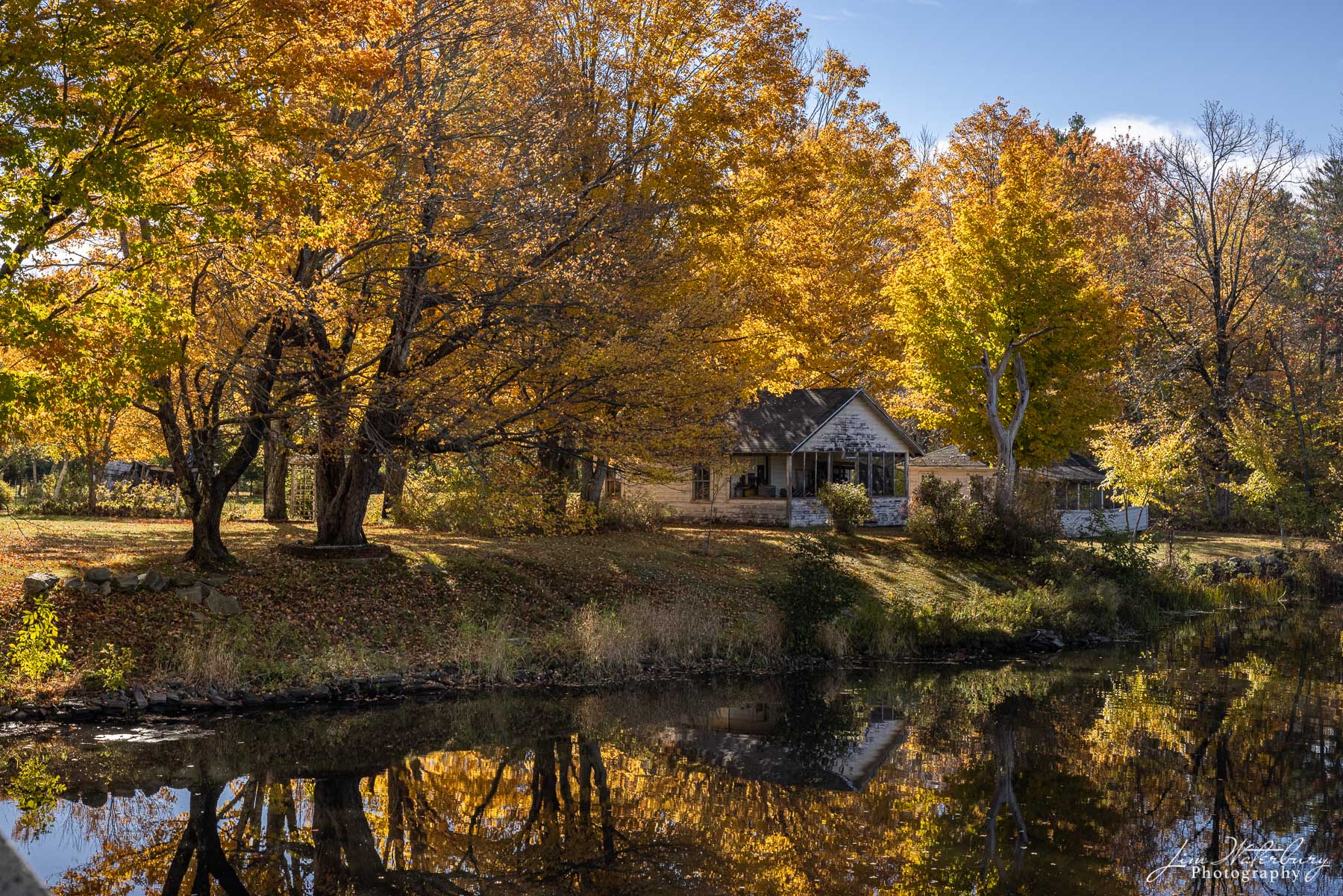 Lake House Small summer cottage on the shores of Damariscotta Lake, Maine, is surrounded by trees showing off brilliant fall colors.