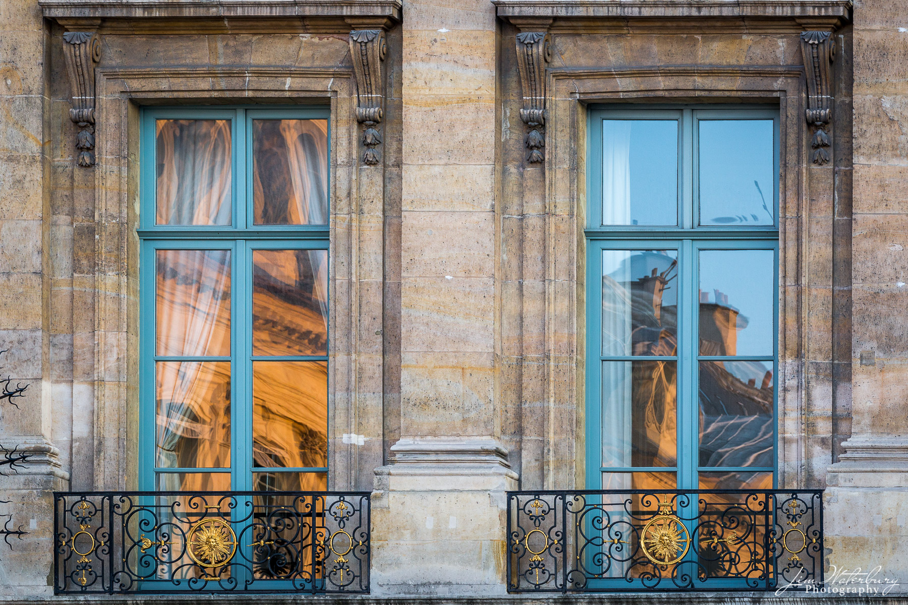 Windows in Place Vendome in central Paris reflect the golden light of sunset shining on the adjacent building.