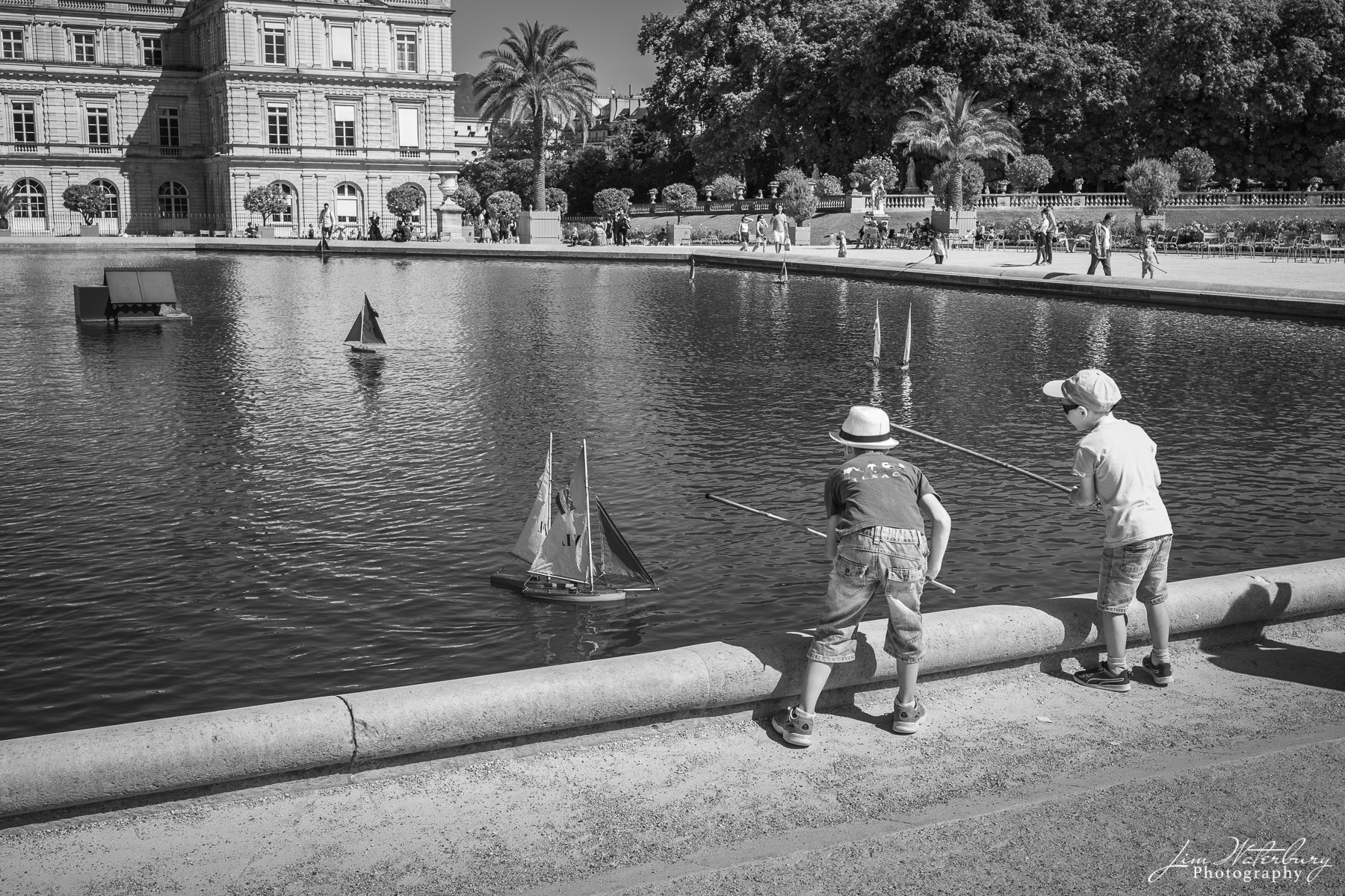 Two boys prepare to race their boats in the pond at the Luxembourg Gardens, Paris. Black & white.