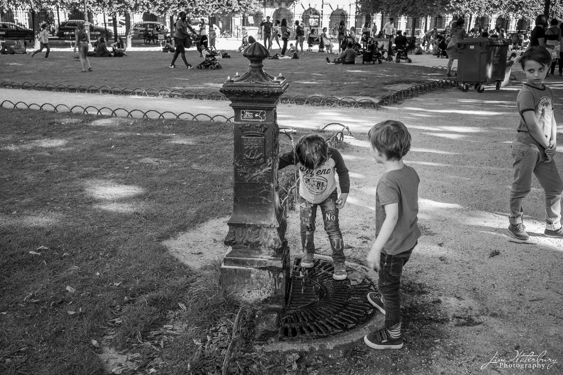 Boys play in the fountain at Place Des Vosges, Paris, after school.  Black & white.