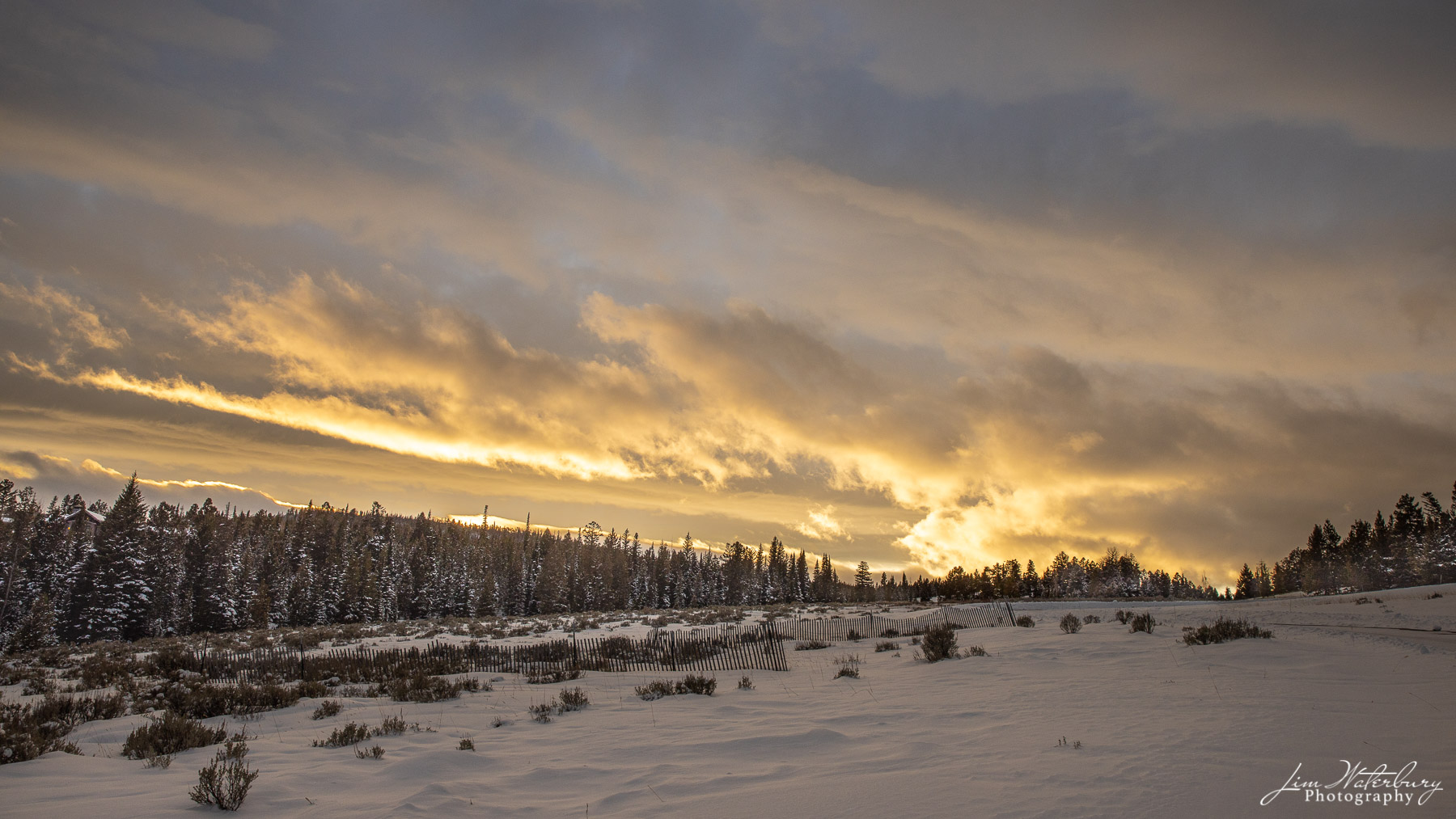 At sunset, the sun shines through darkening storm clouds at Spanish Peaks, Big Sky Ski Resort, Montana.